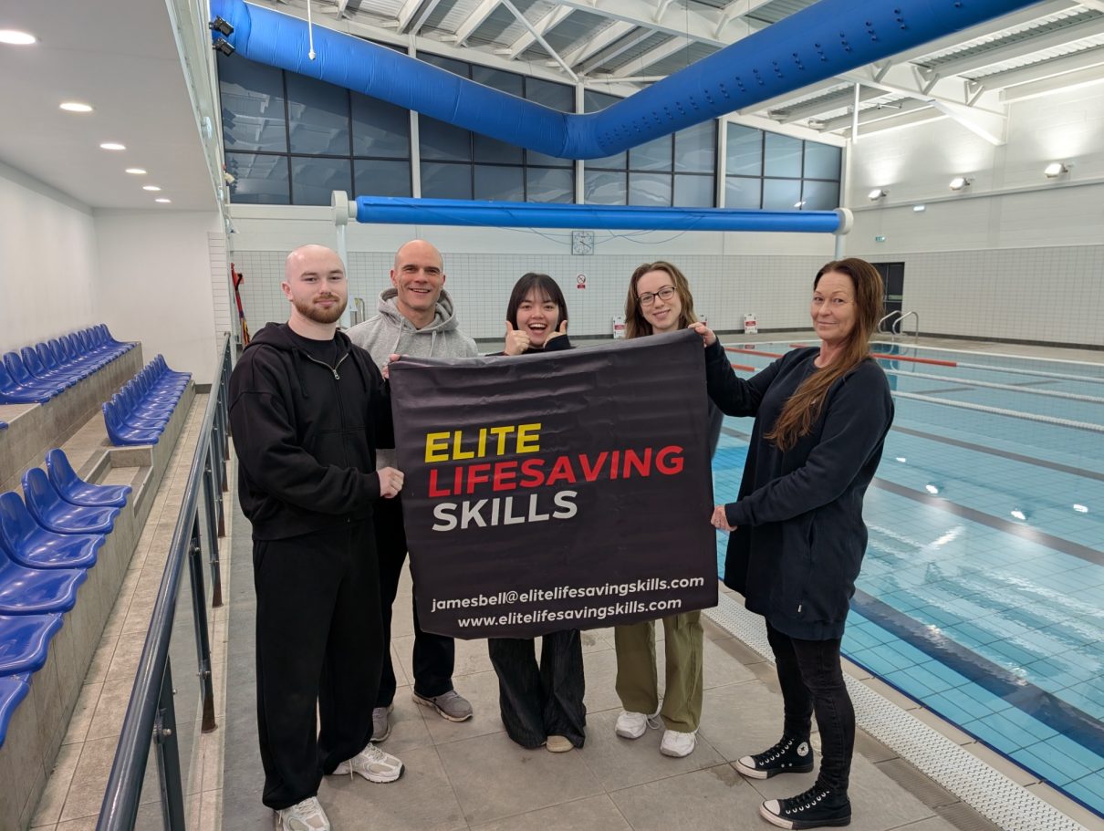 Five people hold a banner reading "Elite Lifesaving Skills" beside a swimming pool.